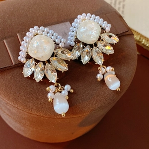Macro di orecchini vintage con perle e cristalli su un portagioie in velluto marrone