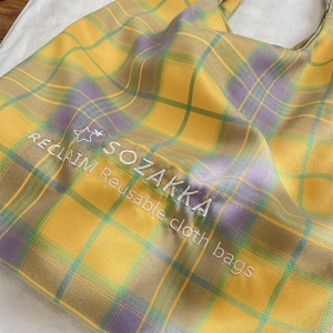 Detail showing high-quality embroidery text on a colorful checkered canvas tote bag