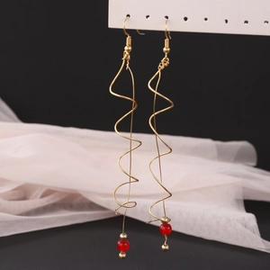 Detail of long gold spiral wave earrings with red beads on a hanging display card