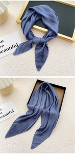 Detail of blue pleated silk scarf showing elegant texture and draped knot styling