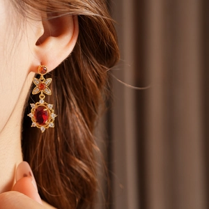Nahaufnahme von Vintage Goldohrringen mit ovalen roten Zirkoniasteinen am Model