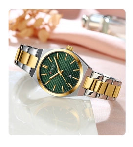 Detail of gold and silver quartz watch with green sunray dial and date window