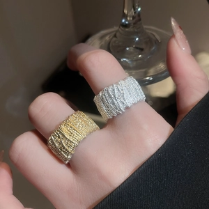 Detail of wide metallic rings with woven texture in gold and silver finish on hand