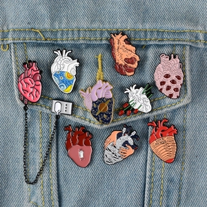 Creative anatomical heart enamel pins with floral and starry night patterns on denim jacket