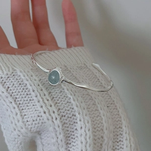 Detailed shot of an irregular S925 silver bracelet with light blue round gemstone on a wrist