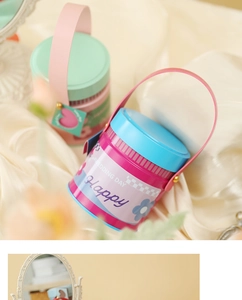 Close-up of pastel macaron metal gift tins with faux leather handles on silk fabric