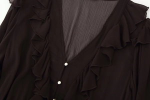 Detail of V-neckline with ruffle trim and silver button on dark brown pleated midi dress