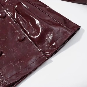 Dettaglio della giacca in ecopelle bordeaux lucida con bottoni e trama del tessuto