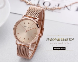 Detail of Hannah Martin rose gold mesh band watch next to a coffee cup and magazine