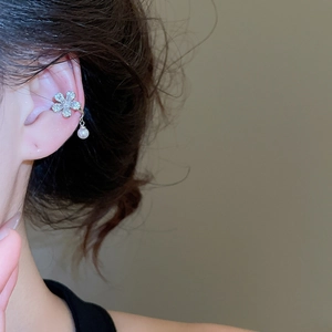 Detail of silver flower ear cuff with sparkling zircons and a white pearl drop pendant