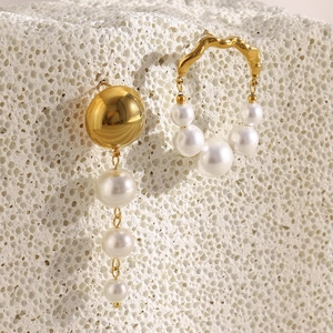 Detail of asymmetric 18K gold plated stainless steel earrings with white faux pearls