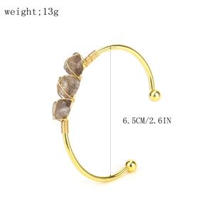 Detail view of handmade gold wire wrapped bracelet with three raw smoky quartz stones