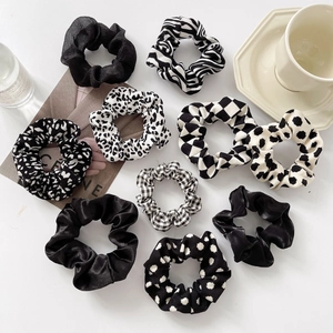 Vue à plat de 10 chouchous noir et blanc aux motifs léopard, damier et zèbre