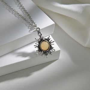 Detailed view of a vintage sun pendant necklace with a yellow gemstone on a silk background