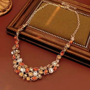 Macro shot of vintage gold necklace with amber rhinestones on a wooden frame