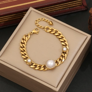 Golden Cuban chain bracelet with round crystal-halo pearl charm on a jewelry box