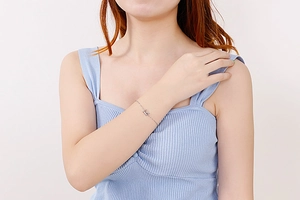 Detail of a silver dainty chain bracelet with a cubic zirconia letter pendant on a wrist