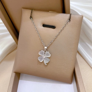 Macro shot of silver four-leaf clover necklace with cat eye stone in jewelry gift box
