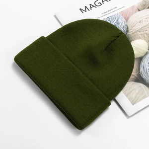 Close-up of fine knit texture on a dark olive green beanie over a white background