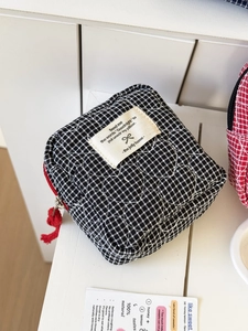 Detail of black and white quilted heart pattern bag with red zipper and fabric label