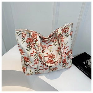 Canvas tote bag with red and green floral print on beige background on a display stand