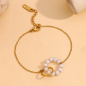Detail of 18K gold plated bracelet featuring white pearl ring and twisted metal loop design