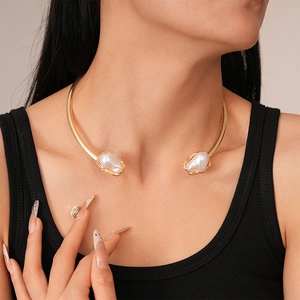 Close-up of golden collar necklace with baroque pearls on elegant model neckline