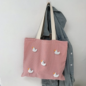 Close-up of red striped canvas tote bag with five cute 3D duck decorations and woven handles