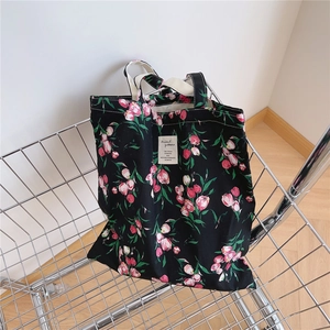 Close-up of floral canvas tote bag with pink tulips leaning against a wire basket