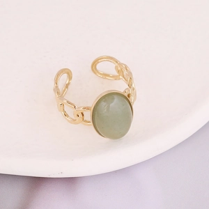 Close-up of gold chain link ring featuring an oval green natural stone on white ceramic