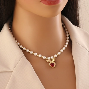 Elegant pearl beaded necklace featuring a red heart pendant with gold leaf accents