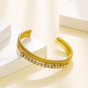 Close-up of golden double-layer C-shaped bangle with fishbone texture and white zircons