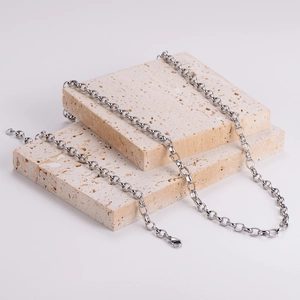 Minimalist silver oval link necklace chain displayed on beige stone platform
