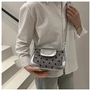Détail du sac à bandoulière argenté à pois avec un nœud en tissu et rabat magnétique