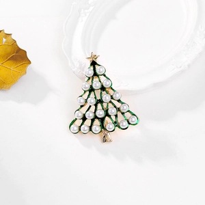 Detail of Christmas tree brooch with green enamel, white pearls and gold star on white background