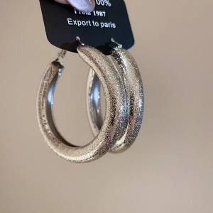 Macro shot of large silver hoop earrings featuring a sparkling sandblasted textured finish