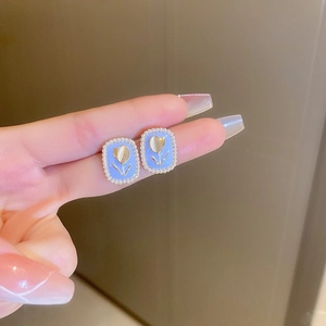 Detailed shot of light blue tulip earrings with pearl edges in a French vintage style
