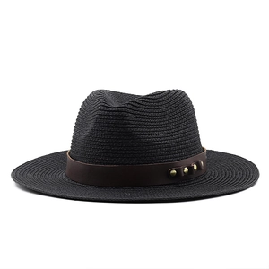 Détail d'un chapeau de paille noir avec ruban en cuir marron et rivets dorés décoratifs