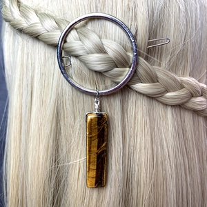 Silver circular hair clip with rectangular tiger eye stone pendant on braided hair