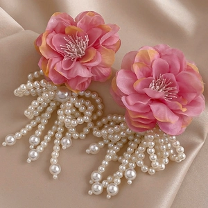 Detail of floral earrings with pink fabric petals and elegant white pearl tassels