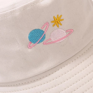 Detailed close-up of colorful planet embroidery and twill texture on a beige cotton bucket hat