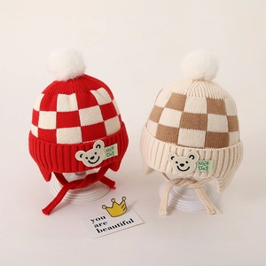 Gedetailleerde gebreide textuur van baby mutsen met dambordpatroon en pluizige pompons