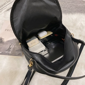Mini black PU leather backpack showing open main compartment with daily essentials inside