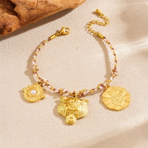 Detail of gold bracelet with leopard head, pearl disc, and heart pendant on rope chain