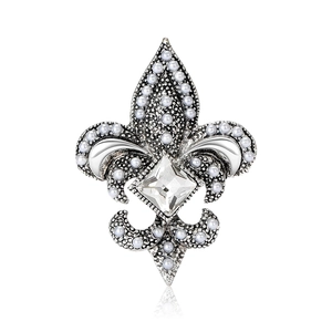 Broche fleur de lys vintage argentée avec perles blanches et cristal sur fond blanc