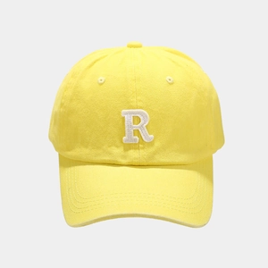 Detail of yellow baseball cap featuring white towel-embroidered R letter on cotton twill fabric