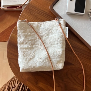 Detail of white cotton linen crossbody bag with floral embroidery and brown leather strap