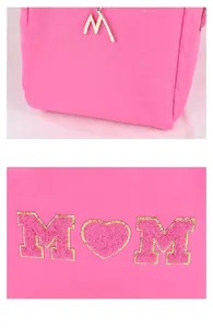 Detail van gouden M-hanger en chenille M-hart borduursel op de roze make-uptas
