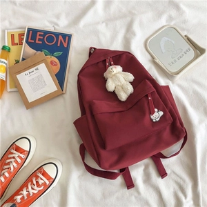 Burgundy minimalist school backpack with white bear keychain and stylish badges