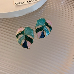 Détail macro des boucles d'oreilles feuille de monstera avec émail coloré et doré